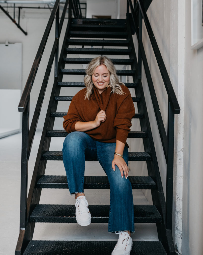 Woman sitting on stairs wearing Burgundy Sweater and Denim Jeans.  SellEatLove.com