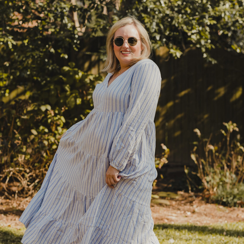 Spring Target Finds - Woman swirling in front of a tree wearing a white and blue striped tiered dress and sunglasses