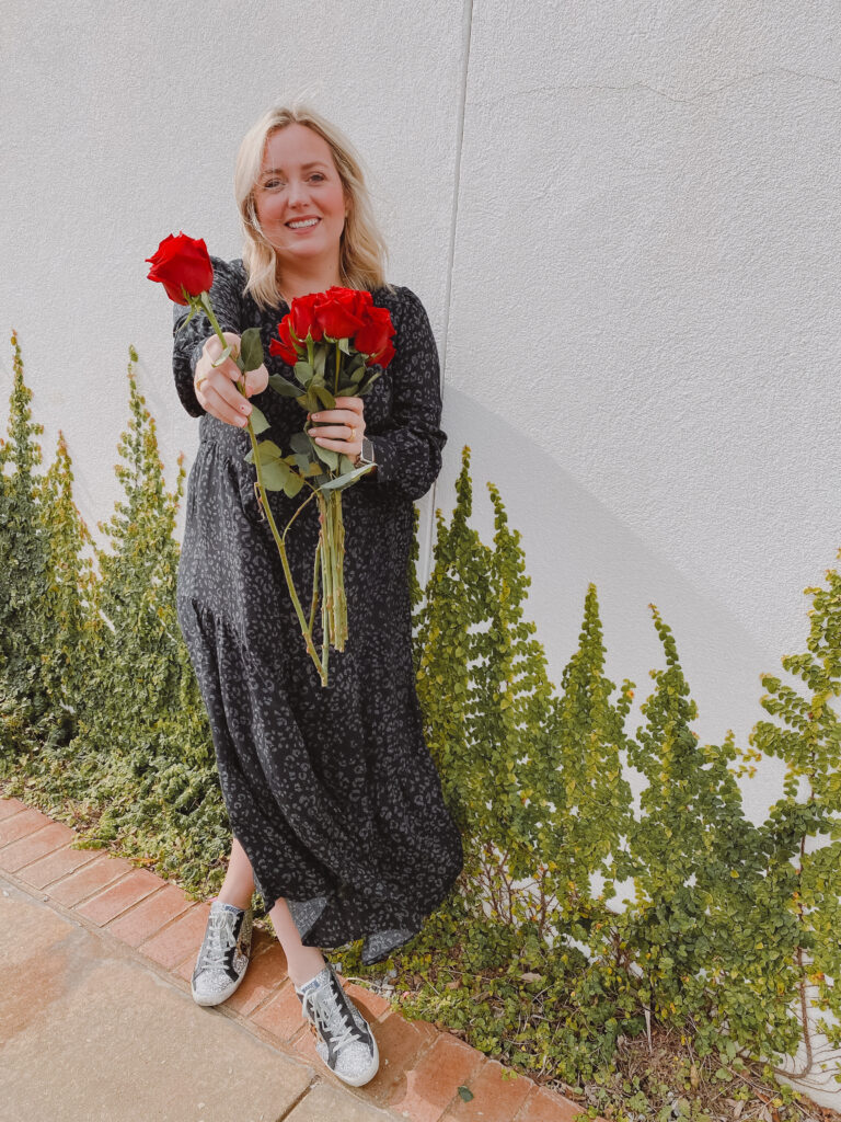 Valentine's Inspired Looks + Gifts + Decor Ideas. Woman wearing long sleeve tiered leopard dress, holding roses outside. 