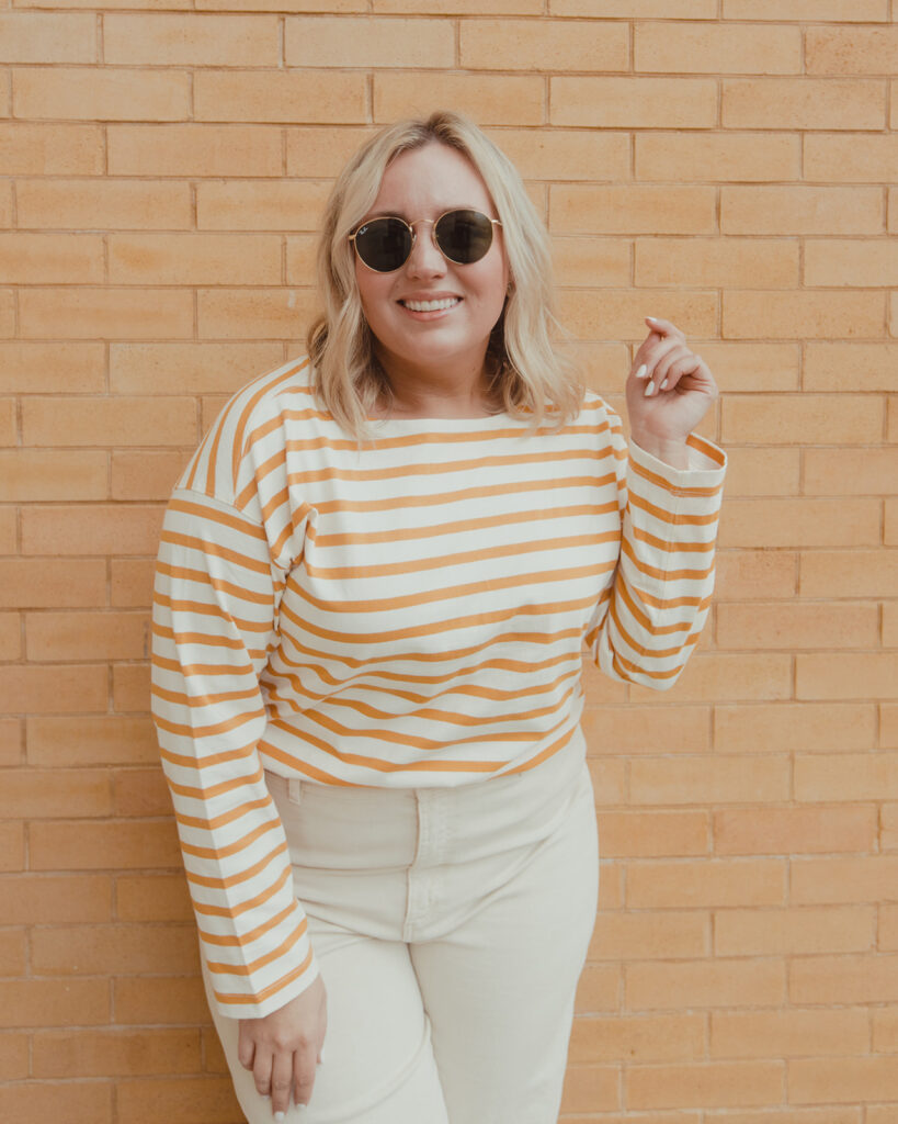 image of woman wearing wide leg pants with striped shirt in front of brick wall