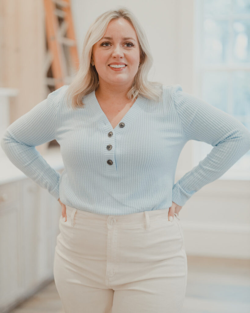 woman standing with hands on hips wearing cream colored wide leg pants and pastel blue button up waffle shirt