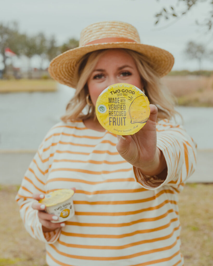 Two Good Yogurt - woman outside in hat holding Two Good Good Save Lemon flavored Greek Yogurt