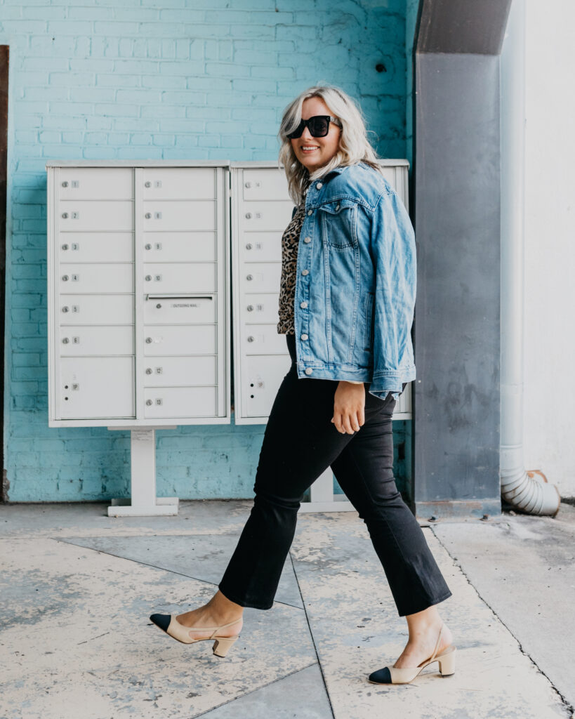 Woman wearing Denim Jacket, Black Denim Jeans and animal print top.