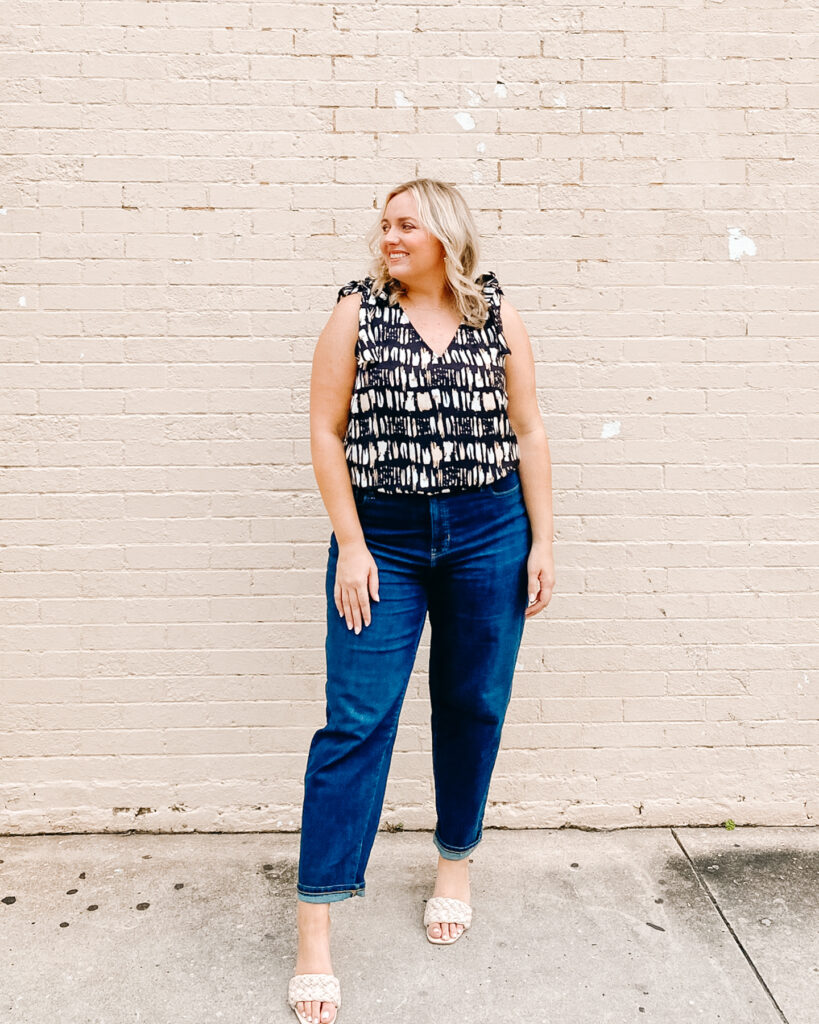 Woman Standing in front of brick wall wearing Sleeveless top and Denim Jeans from Banana Republic. SellEatLove.com